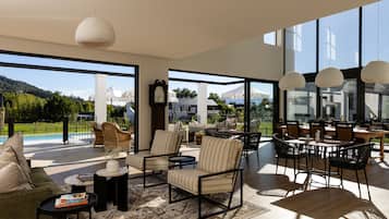 A spacious living area with a large window, a dining table, and comfortable seating.
