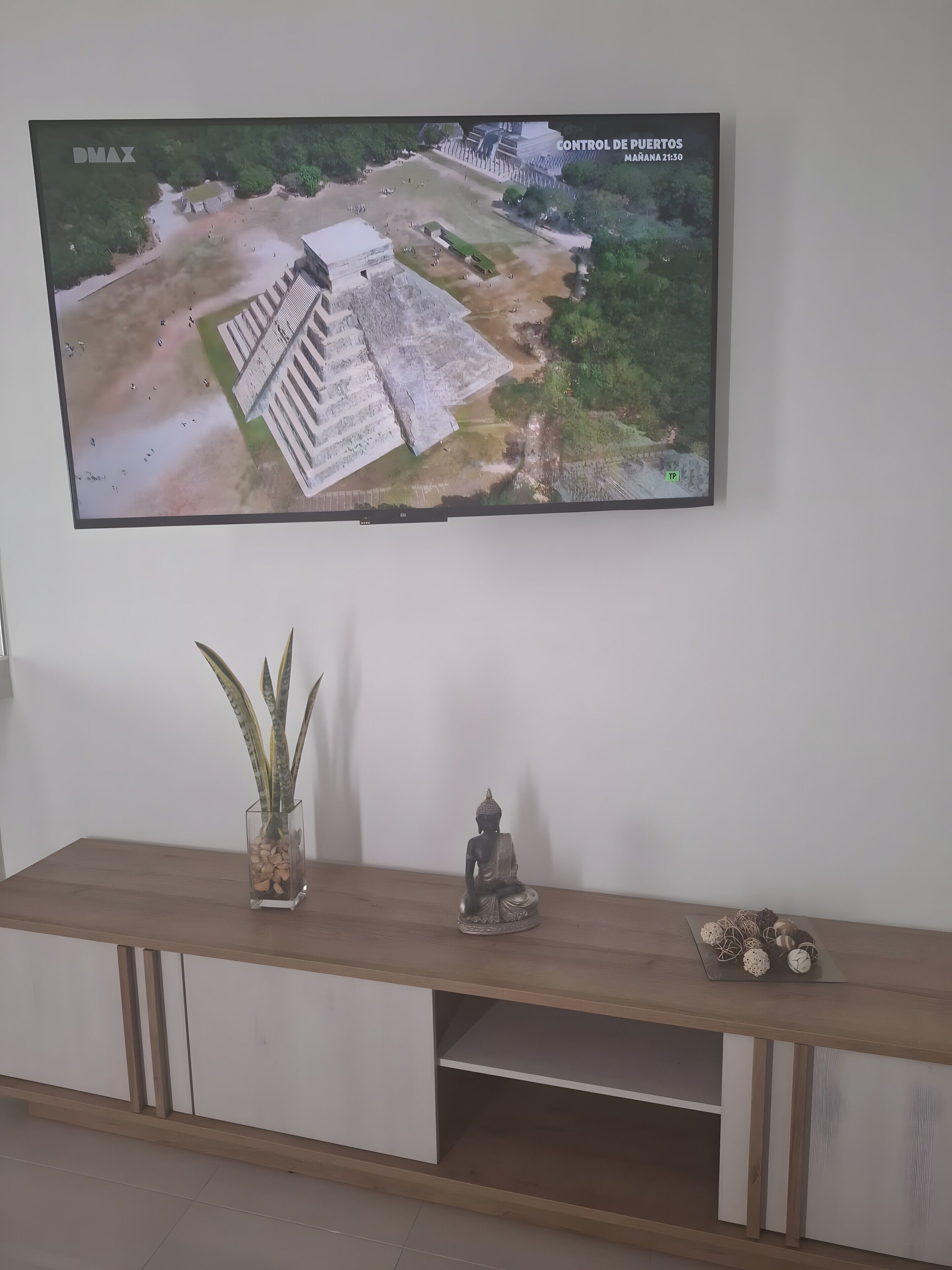 Een televisie aan een muur bevestigd, toont een overzicht van een historisch gebouw.