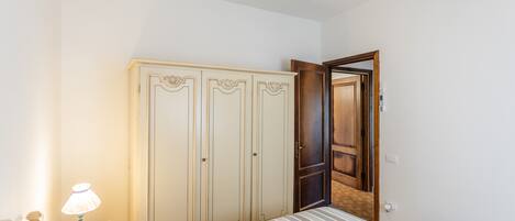 Une chambre à coucher comprenant un lit, une armoire, un ventilateur de plafond et une table de chevet avec une lampe.