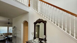 Eine Treppe mit weißen Balustraden und einem hölzernen Geländer, die zu einer oberen Etage führt.