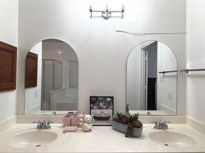 Une salle de bain avec deux lavabos, un grand miroir et une statuette d’ours décorative.