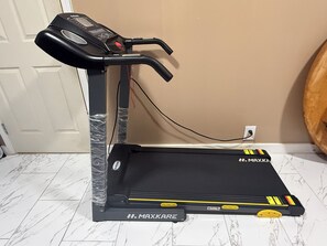 Un vélo d’appartement, doté d’un écran numérique et d’un panneau de commande, est placé sur un sol carrelé.