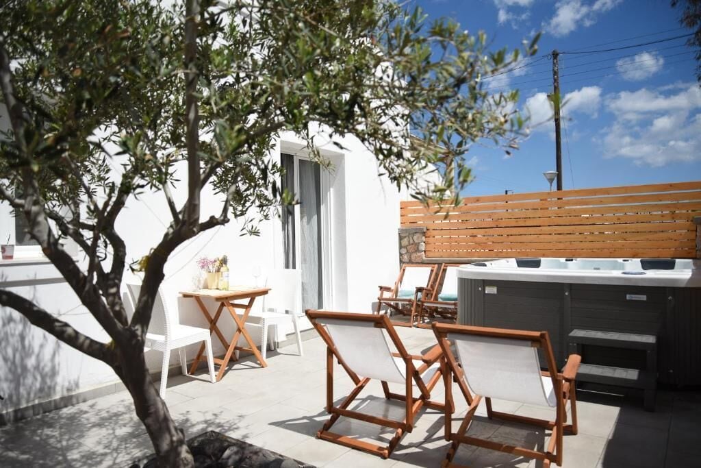 Un patio con mobiliario exterior, un jacuzzi y un árbol.