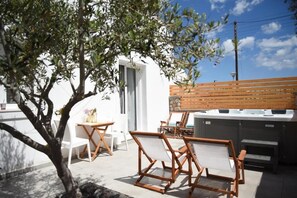 Eine Terrasse mit Gartenmöbeln, einem Whirlpool und einem Baum.