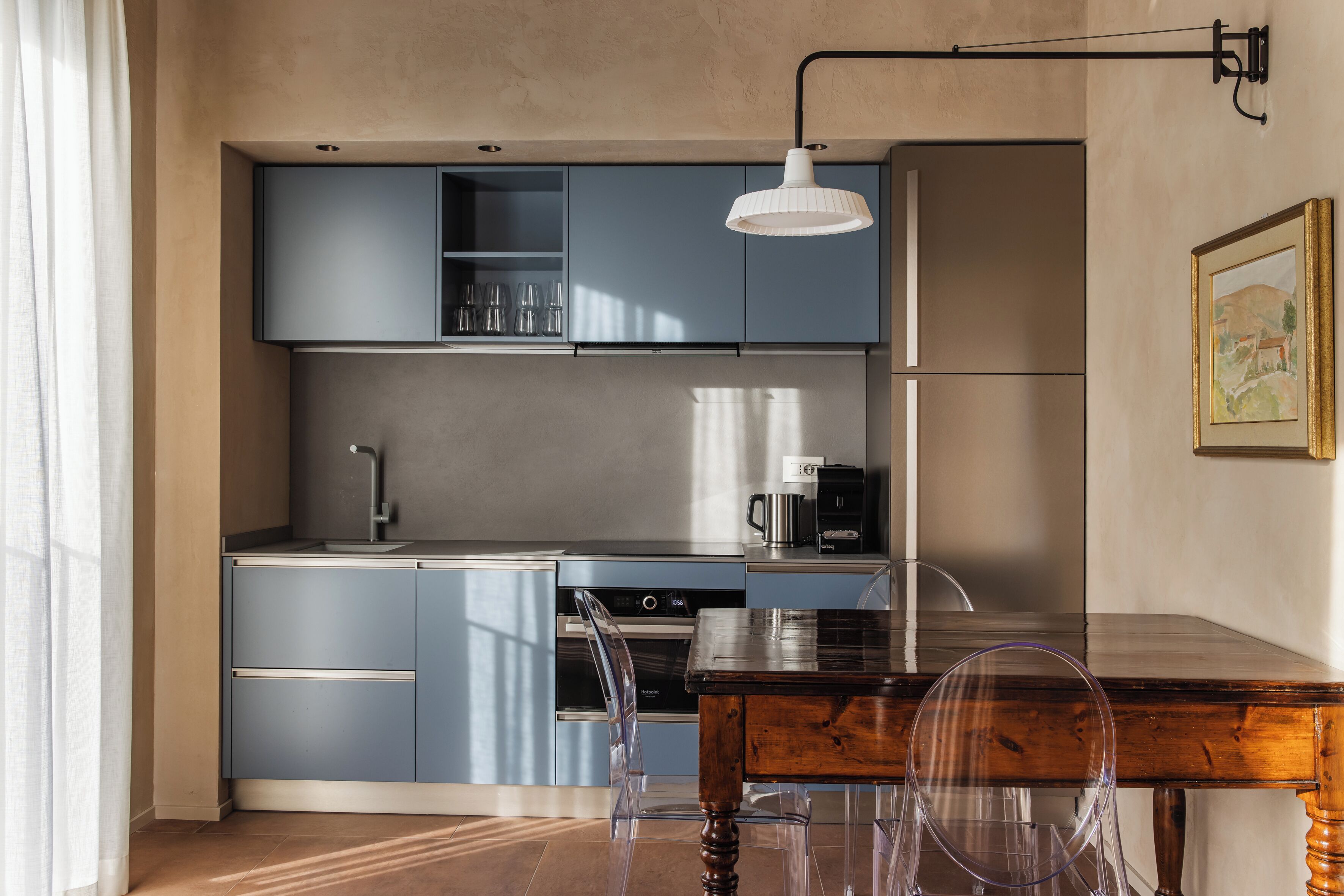 A modern kitchen with blue cabinets, a coffee machine, and a dining table with chairs.