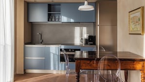 A modern kitchen with blue cabinets, a coffee machine, and a dining table with chairs.