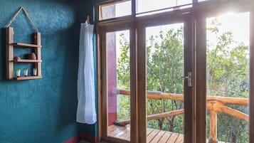 A room with a wooden shelf, a curtain, and a view of a balcony with a railing.
