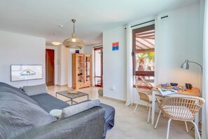 Un salon comprenant un canapé, une table basse, une table à manger avec des chaises, une bibliothèque et un téléviseur.