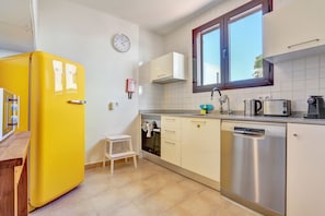 A kitchen with a yellow refrigerator, white cabinets, a dishwasher, and a window with a view. - Villa VERO -  Private villa in Playa Blanca (Playa Blanca)
