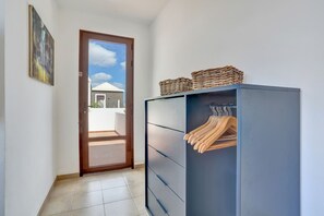 Ein Flur mit einem Kleiderschrank, einer zur Außenseite führenden Tür und einem gefliesten Boden.
