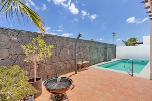 A pool area with a stone wall, a grill, and a small table. - Villa VERO -  Private villa in Playa Blanca (Playa Blanca)