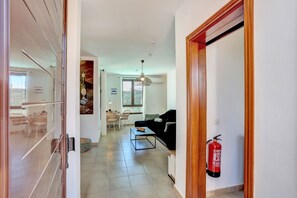 A hallway leading to a living area with a sofa, a dining table, and chairs. A fire extinguisher is mounted on the wall. - Villa VERO -  Private villa in Playa Blanca (Playa Blanca)