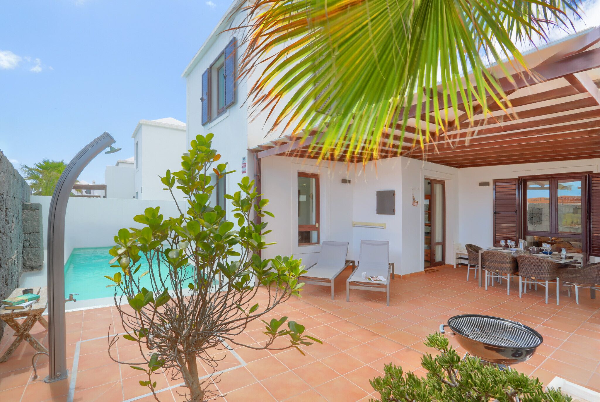 Une villa avec piscine, un espace salon extérieur et une terrasse couverte.