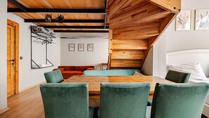 Et moderne interiør med træloft, spisebord med stole, sofa og seng.