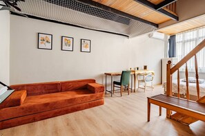 Ein modernes Wohnzimmer mit einer Holzbank, einem roten Sofa, einem Esstisch mit Stühlen und einer Treppe.