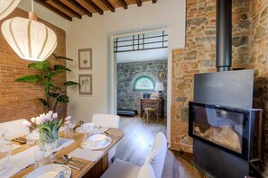 Un coin repas avec une table dressée pour quatre personnes, une cheminée et un mur en pierre.