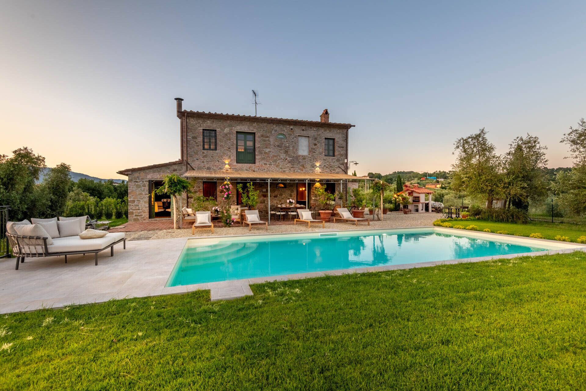 Uma casa de pedra com piscina, área de estar ao ar livre e um jardim.