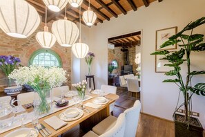 A dining area with a stone wall, hanging light fixtures, and a large potted plant. - Villa Pellegrini with breathtaking view (Montecarlo)