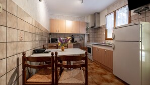 A compact kitchen with a dining table, chairs, a refrigerator, and a microwave.