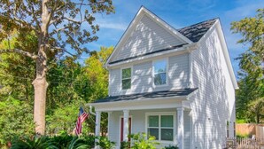A two-story white house with a front porch, an American flag, and a mailbox.