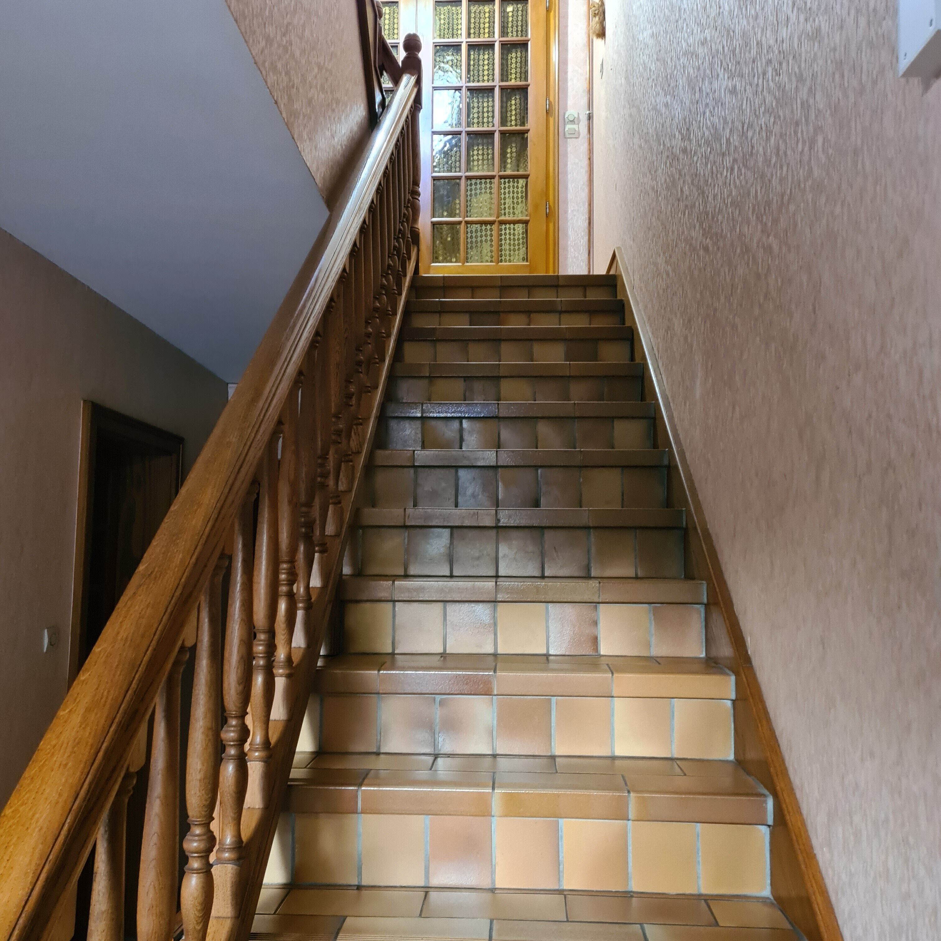 A staircase with wooden balusters and terracotta tiles.
