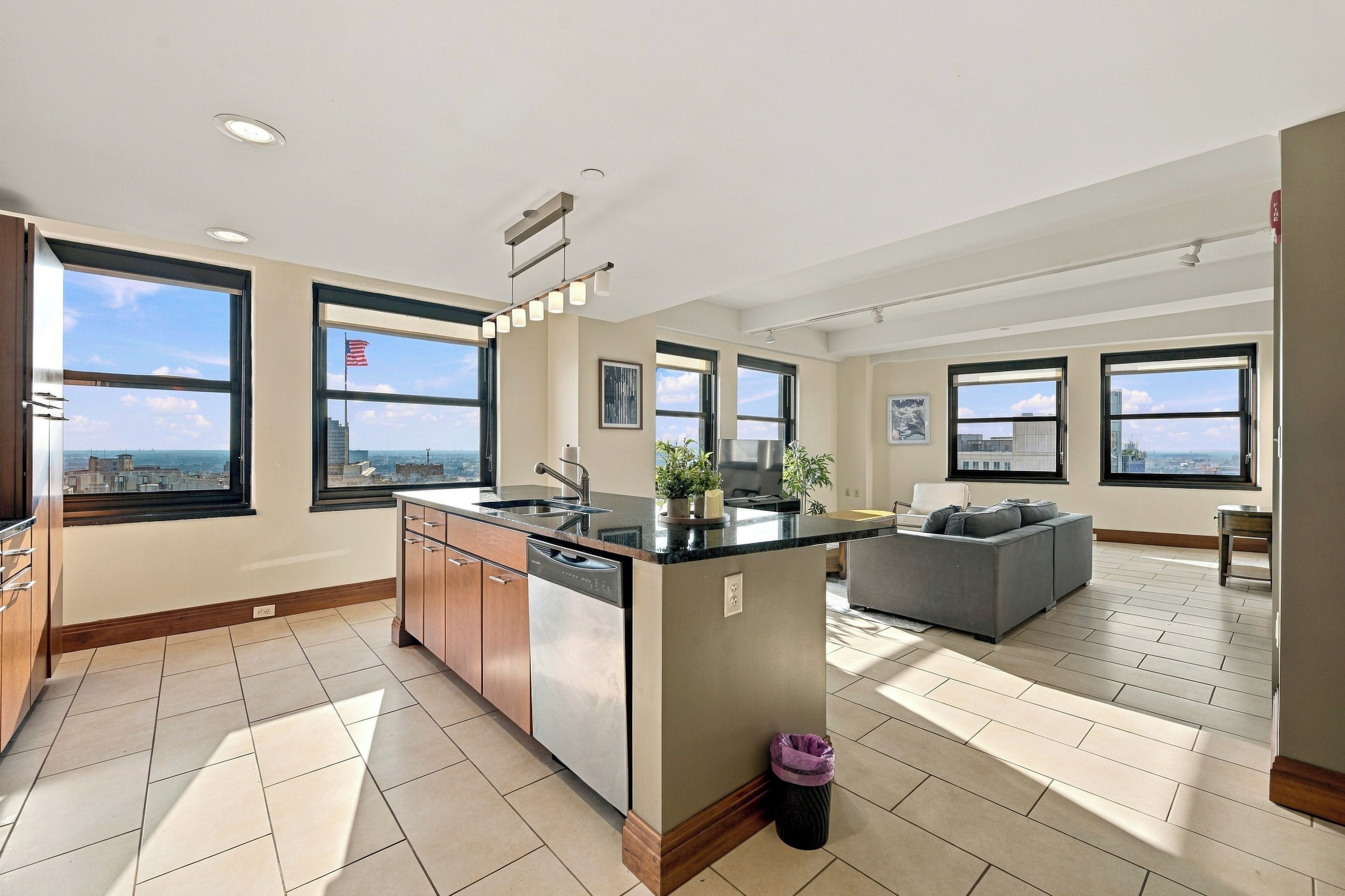 Eine moderne Wohnung mit Küche, Essbereich und Wohnzimmer, ausgestattet mit großen Fenstern und Blick auf die Stadt.