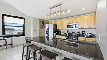A modern kitchen with a large island, stainless steel appliances, and wooden cabinets.