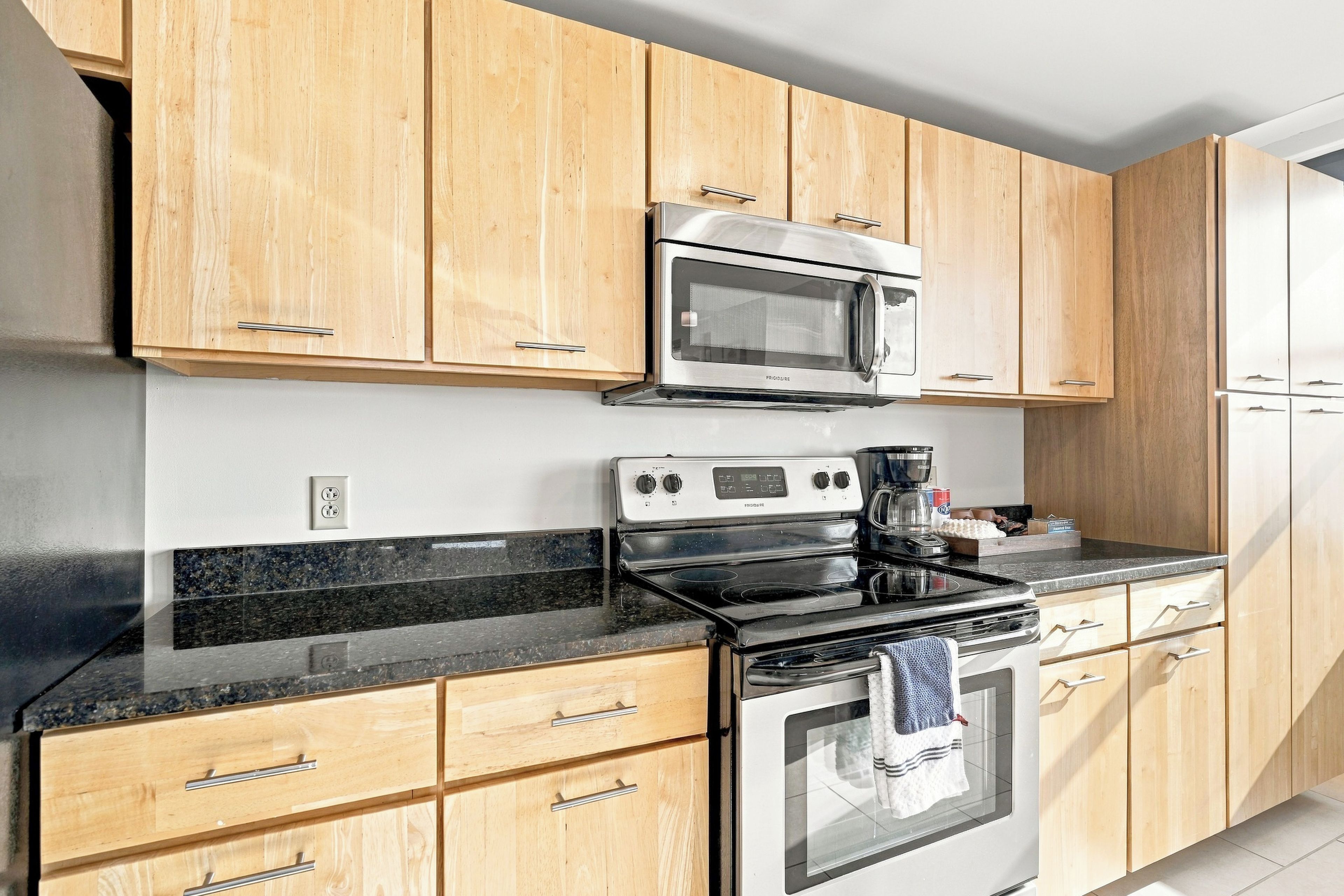 A kitchen with wooden cabinets, a microwave, a stove, and a refrigerator.