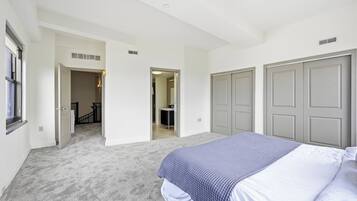 Een slaapkamer met een bed, een inloopkast en een badkamer, zichtbaar door een open deur.
