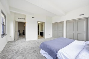 A bedroom with a bed, a closet, and a bathroom visible through an open door.