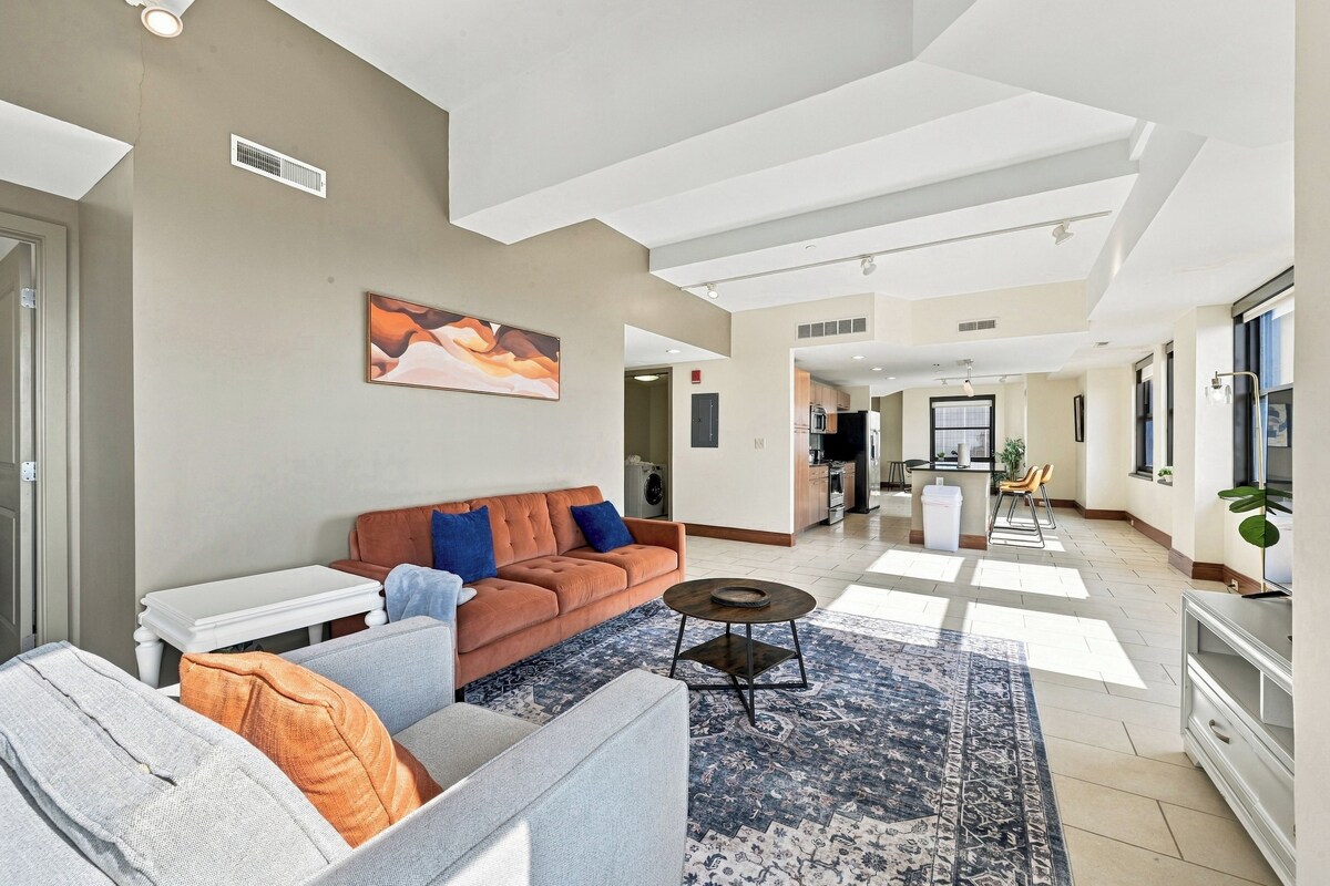 A spacious living area with a sofa, coffee table, and a rug.
