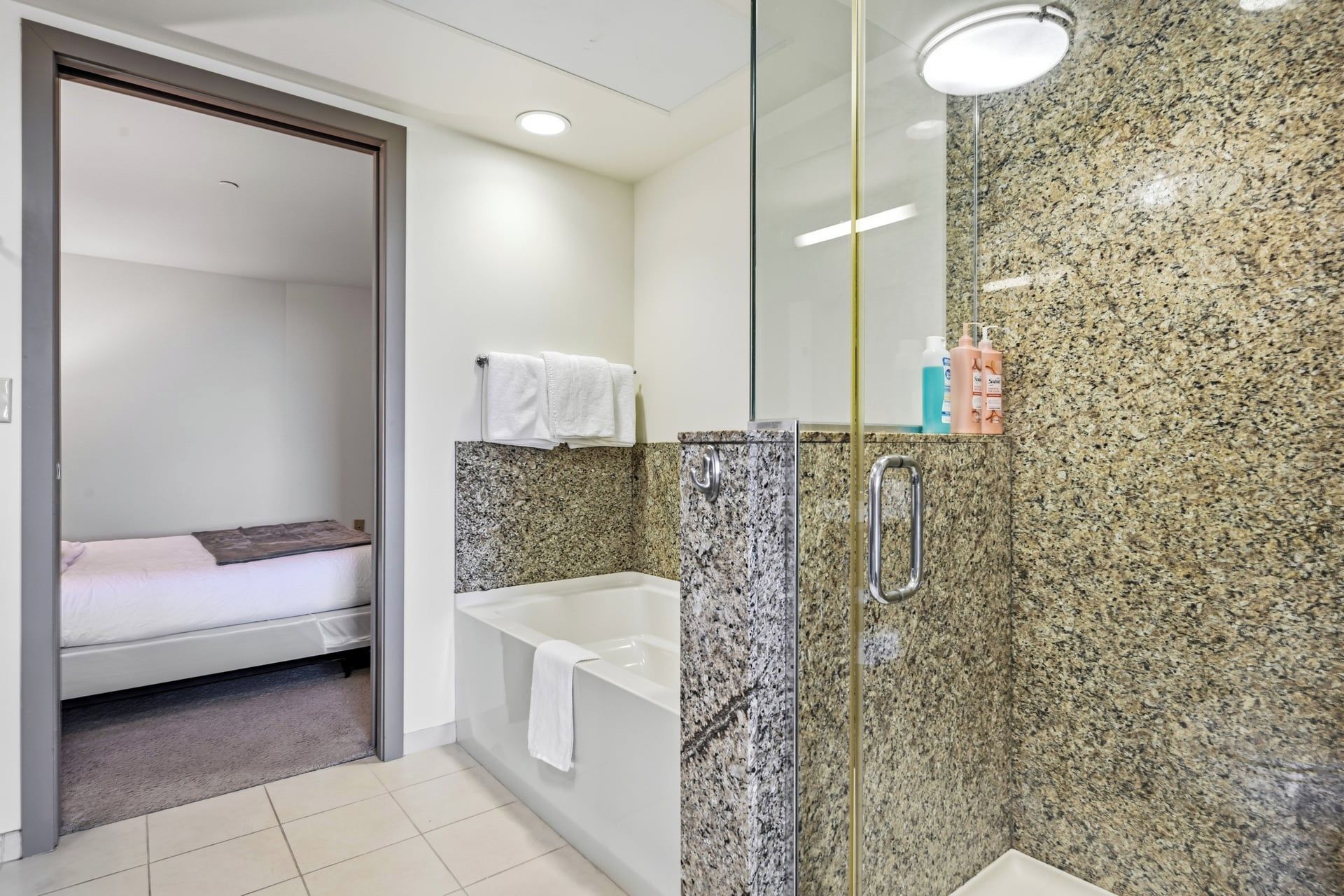 A bathroom with a shower, a bathtub, and a toilet. There is a towel hanging on the wall.