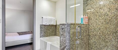 A bathroom with a shower, a bathtub, and a toilet. There is a towel hanging on the wall.