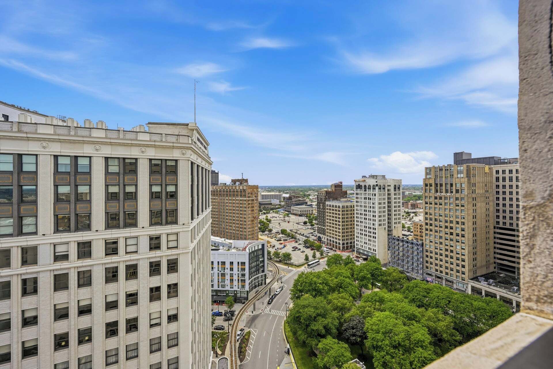Un paisaje urbano con edificios altos, cielo despejado y una carretera con vehículos.