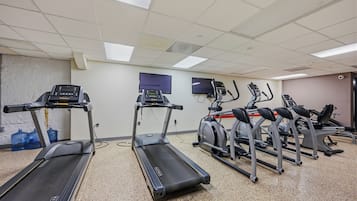 Un gimnasio con cintas de correr, elípticas y bicicletas estáticas.
