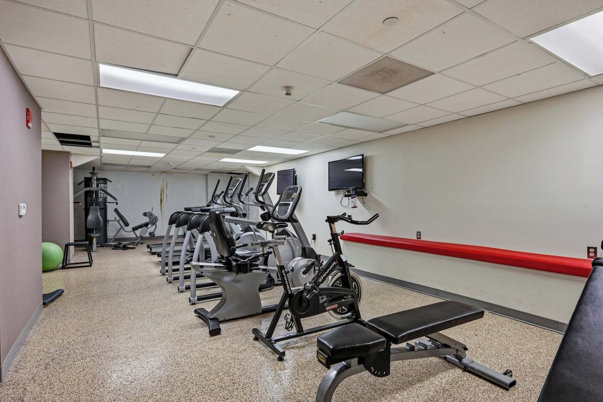 Une salle de sport équipée de tapis de course, de vélos d’appartement et d’un banc de musculation.