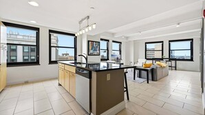 A modern kitchen with a central island, large windows, and a view of the cityscape.