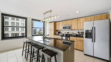 A modern kitchen with a central island, stainless steel appliances, and wooden cabinets.