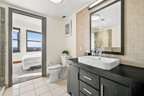 A modern bathroom with a large mirror, a white sink, and a toilet.
