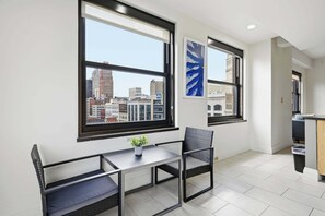 A modern room with a city view, a dining table, and a chair. - 2 BR Iconic Detroit High-Rise Loft (Detroit)