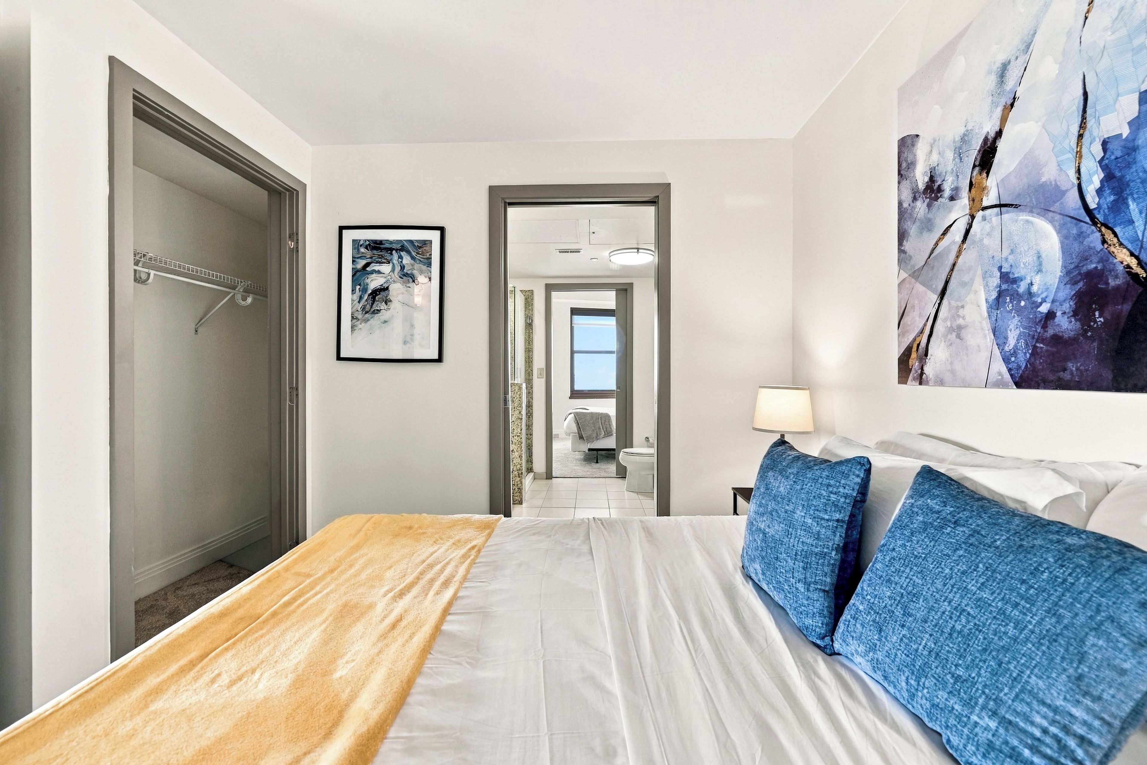 Ein Hotelzimmer mit einem Bett, einem Gemälde, einem durchgegangenen Tür angedeuteten Badezimmer und einer Duschkabine.