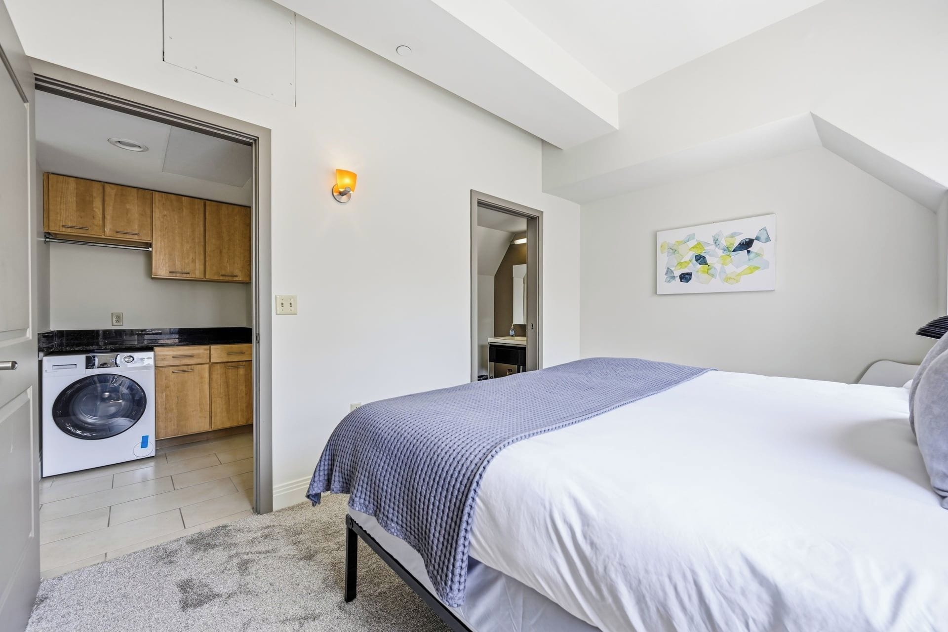 Une chambre avec un lit, un lave-linge et un coin cuisine.