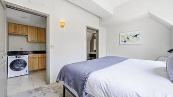 Une chambre avec un lit, un lave-linge et un coin cuisine.
