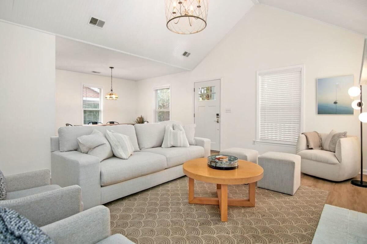 A modern living room with a light grey sofa, a round wooden coffee table, and a patterned rug.