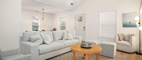 A modern living room with a light grey sofa, a round wooden coffee table, and a patterned rug.