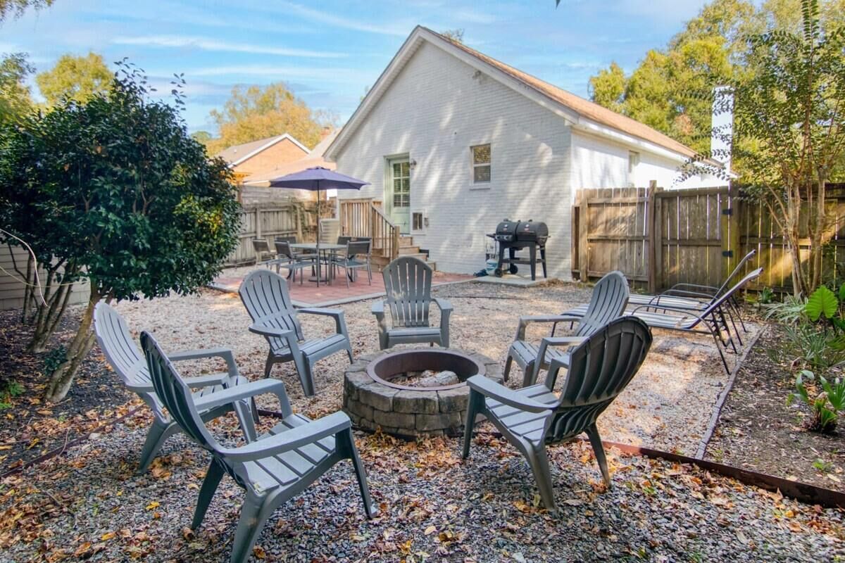 A backyard with a fire pit, outdoor seating, and a barbecue grill.