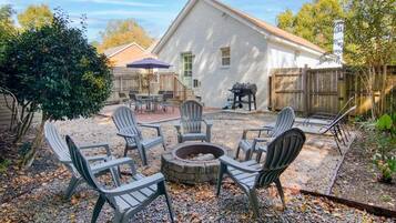 A backyard with a fire pit, outdoor seating, and a barbecue grill.