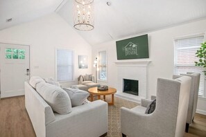 Una sala de estar moderna con chimenea, un conjunto de sofás y un televisor montado en la pared.