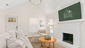 En moderne stue med en hvid sofa, et rundt træbord og en pejs.