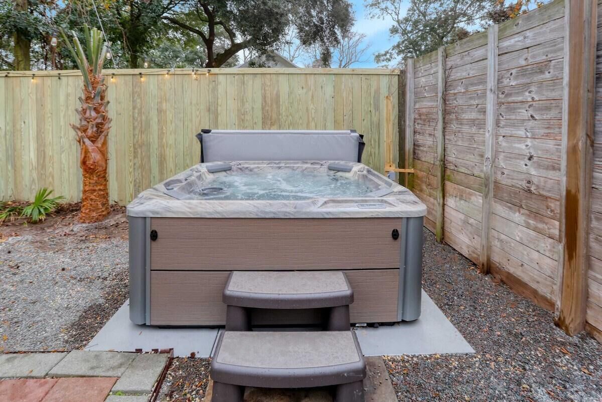 Ein Whirlpool mit eingebautem Sitz und Stufen, umgeben von einem Holzzaun und einer Palme.